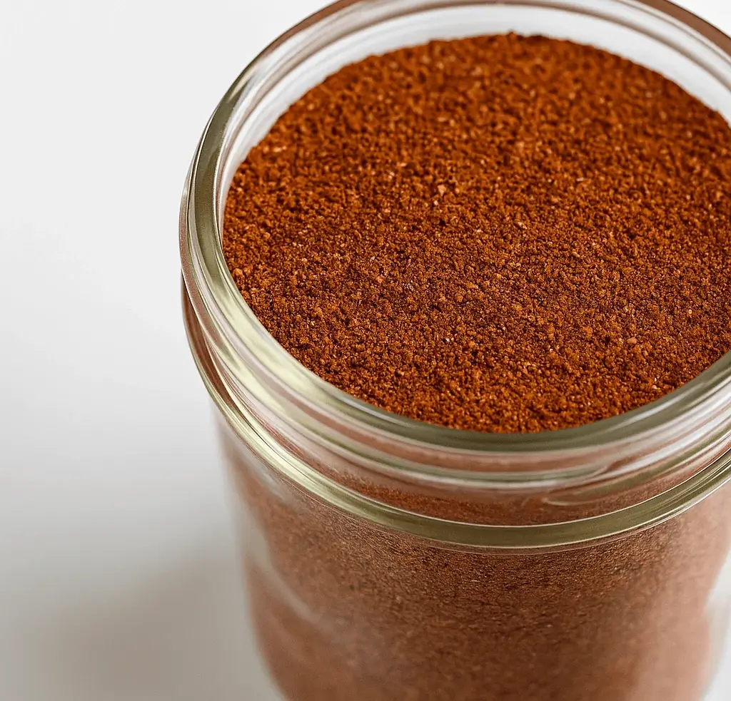 Homemade chili seasoning recipe blend in a glass jar on a white background