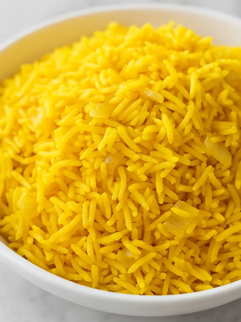 Close-up of a bowl filled with fluffy yellow rice with visible cooked onions.